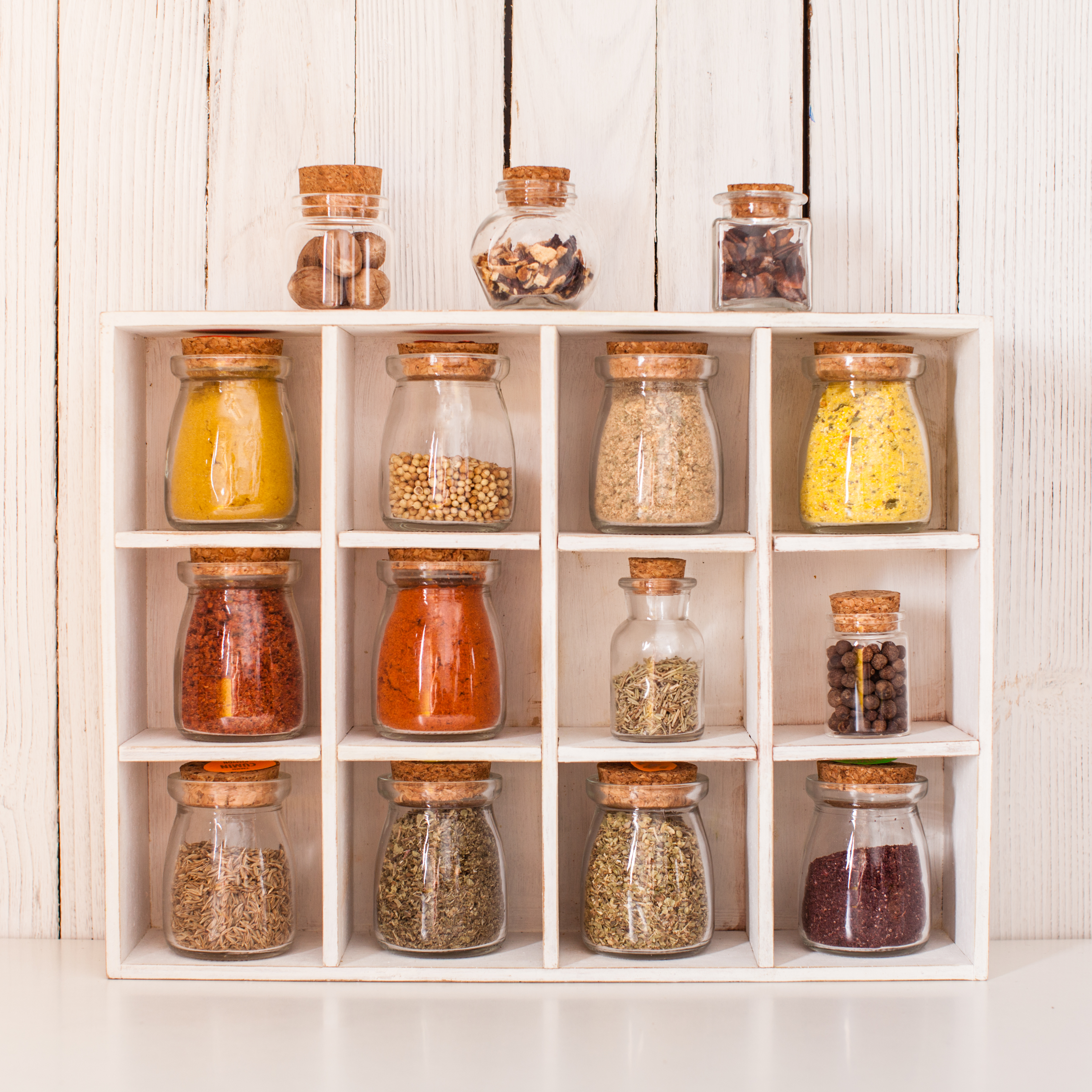 Assortment of dry spices in vintage glass bottles in wooden box
